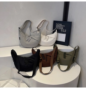Detail view of five nylon crescent crossbody bags in various colors on white stands