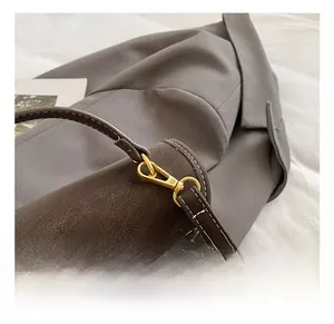 Detail showing high-quality golden metal buckle and white stitching on brown leather bag