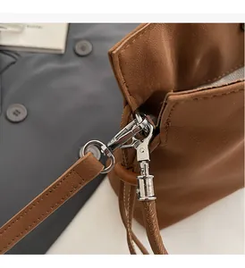 Detail of brown leather bag showing premium silver hardware and stitching on grey suit