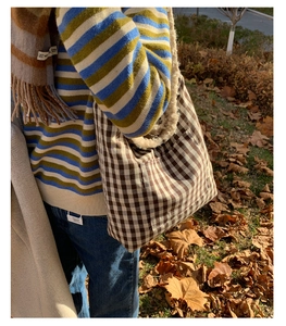 Close-up of brown gingham tote bag with soft fleece handle in an autumn setting