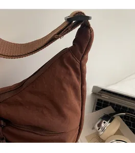 Detail of soft caramel nylon crossbody bag with adjustable strap on a minimalist desk
