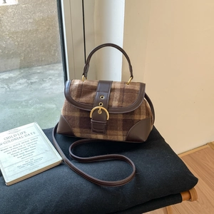 Close-up of vintage brown plaid handbag with golden buckle and leather trim detail