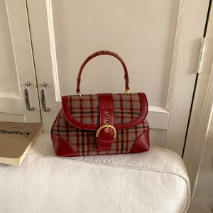 Detail of red and blue tartan handbag with premium leather trim and golden horseshoe buckle