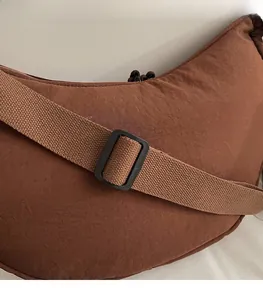 Close-up of adjustable strap detail on brown water-resistant nylon crescent shoulder bag