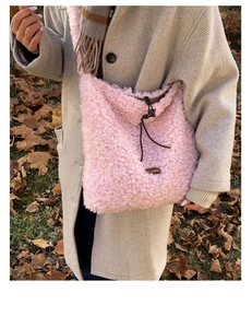 Detail of pink faux fur crossbody bag featuring brown drawstring and leather logo patch