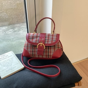 Detail of vintage plaid bag with red leather trim and golden buckle on black seat
