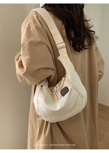 Détail du sac à bandoulière en toile blanc cassé avec écusson brun et sangle réglable