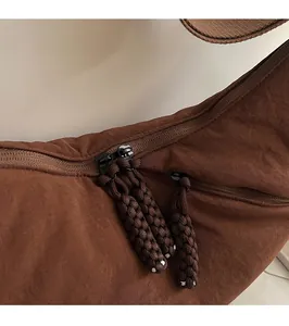 Detailed macro view of dark brown fabric bag featuring dual metal zippers with braided tassels