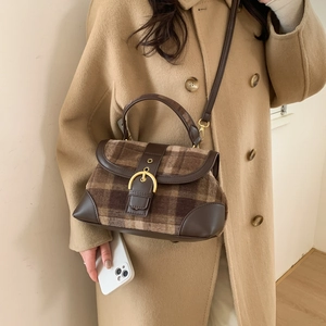 Detail of vintage plaid handbag with golden horseshoe buckle and brown leather trim