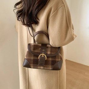 Detail view of vintage brown checkered crossbody bag with golden horseshoe buckle and leather strap