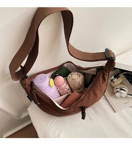 Interior storage view of brown crescent crossbody bag holding umbrella, bottle and phone