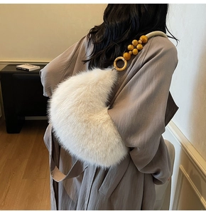 Détail du sac croissant en peluche montrant la bandoulière tressée et perles en bois