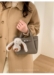 Détail du sac seau gris en cuir avec fermoir rotatif argenté et pendentif lapin