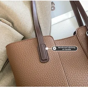 Detail of reinforced stitching on the brown lychee pattern leather tote bag handle