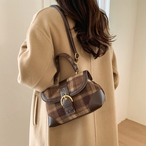 Detail view of brown plaid handbag with gold ring buckle and adjustable leather strap