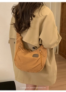 Detail view of vintage canvas crescent bag worn over a beige coat in retro style