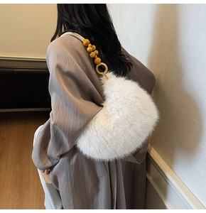 Detail of white plush hobo bag featuring ethnic style wooden beads on the strap