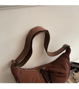 Detail of wide woven strap and dark brown braided zipper pull on a brown canvas bag