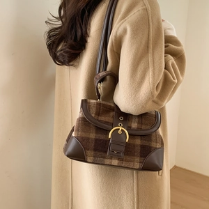 Detail of retro plaid handbag with gold metal ring buckle on model wearing beige coat