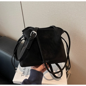 Detail of black matte suede bucket bag with adjustable leather strap and drawstring