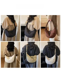 Detail of minimalist dumpling bag showing wide shoulder strap and woven zipper pullers