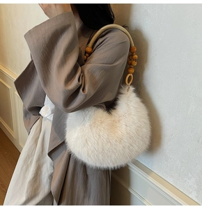 Détail d'un sac d'épaule en fausse fourrure avec poignée en perles de bois et forme demi-lune
