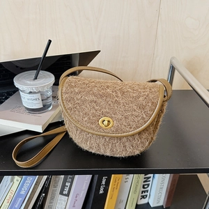 Dettaglio della borsa a sella in peluche marrone con finitura in ecopelliccia e chiusura dorata