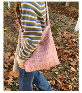 Detail of pink plaid tote bag featuring fluffy fleece lining and 'lay down' side label