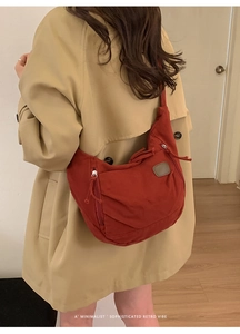Detail of red retro canvas crescent bag featuring pleated design and top zipper closure