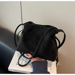 Close-up of black frosted leather bucket bag with metallic logo and drawstring detail