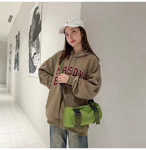 Detail einer hellgrünen Nylon-Zylindertasche kombiniert mit einem braunen Hoodie