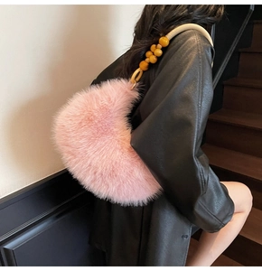 Détail du sac croissant en fausse fourrure rose avec perles d'ambre sur la poignée