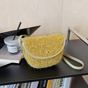 Dettaglio borsa a sella in peluche giallo con chiusura dorata su scrivania casual