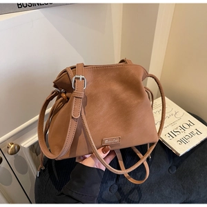 Detail of caramel brown bucket bag with pleated design and silver buckle strap