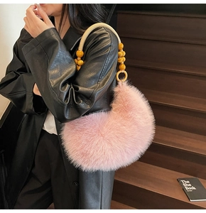 Détail du sac en fausse fourrure rose avec anse perlée porté à l'épaule dans l'escalier