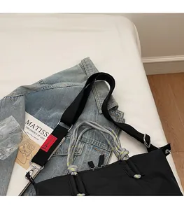 Détail du cabas en nylon noir avec anses tressées et bandoulière textile réglable