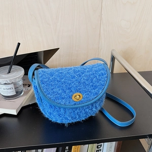 Dettaglio borsa a sella blu in peluche con chiusura dorata e tracolla in pelle liscia