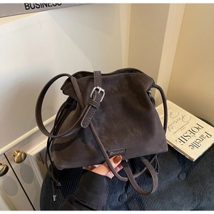 Detail view of dark brown frosted suede bucket bag with adjustable strap and drawstring charm