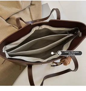 Detail view of large brown tote bag interior with zipper compartments and plush charm