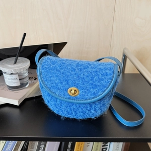 Dettaglio borsa a sella in peluche blu con chiusura in metallo dorato e tracolla