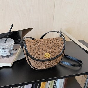 Dettaglio borsa a sella leopardata con chiusura dorata e rifinitura in pelle nera