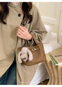 Détail du sac seau en cuir marron avec fermoir argenté et breloque lapin gris