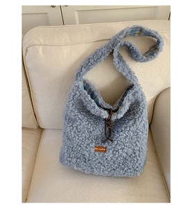 Detail of light blue fuzzy tote bag showing plaid lining and brown leather drawstring