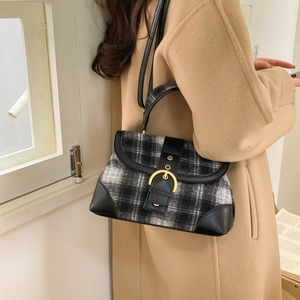 Detail of checkered shoulder bag with gold metal buckle worn with a beige coat