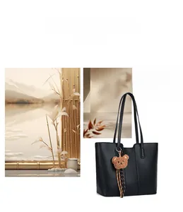 Detail of black pebbled leather tote bag with a cute brown plush bear charm