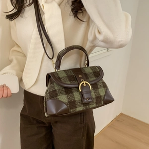 Close-up of green checkerboard tweed handbag with brown leather trim and gold buckle detail