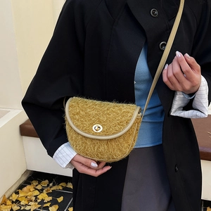 Dettaglio borsa a sella in peluche giallo con chiusura dorata e finiture in eco