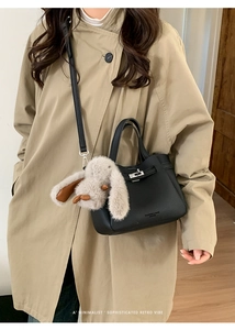 Détail du sac à main en cuir grainé noir avec fermoir rotatif argenté et porte-clé lapin