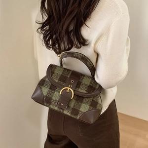 Detail of vintage green plaid handbag featuring leather trim and gold horseshoe buckle