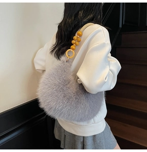 Detail of plush faux fur hobo bag featuring decorative yellow wooden beads and woven strap